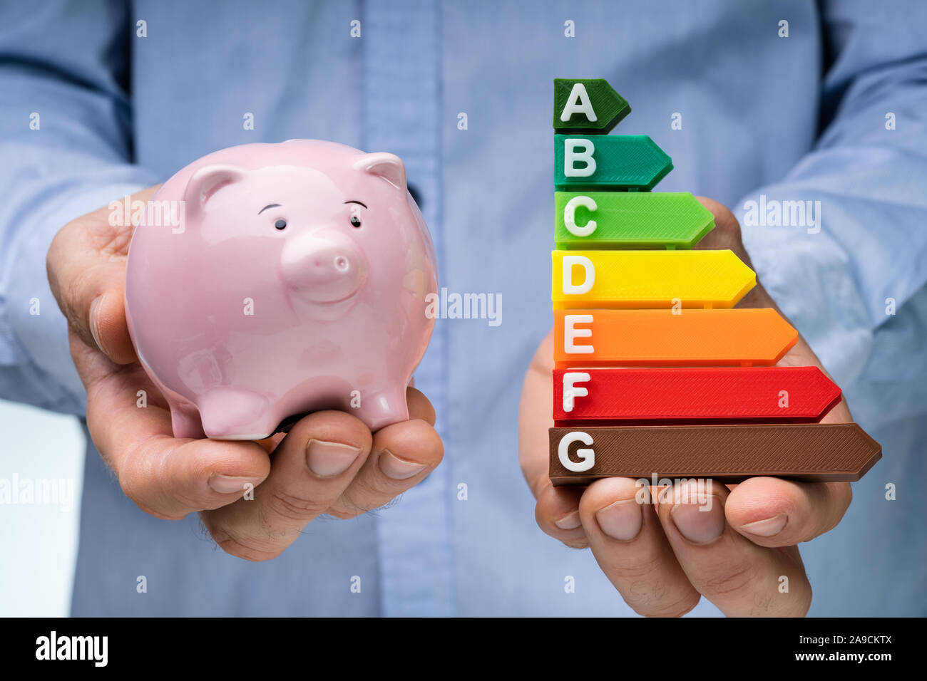 La sezione centrale di una mano di un uomo Azienda Piggybank rosa e colorato Efficienza Energetica grafico Foto Stock