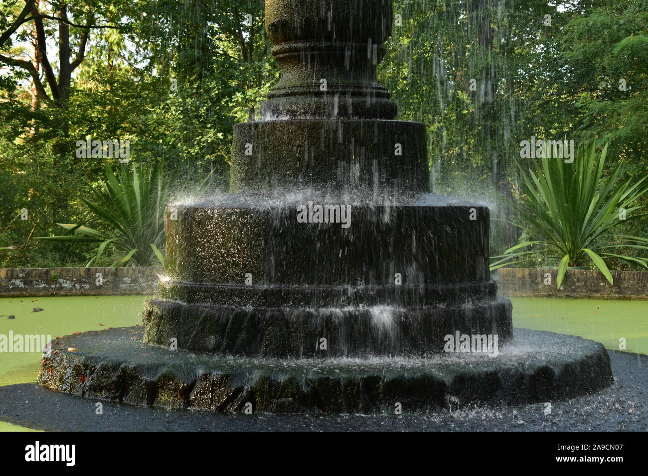 Una lunga esposizione di acqua che cade in una fontana in un giardino in estate Foto Stock