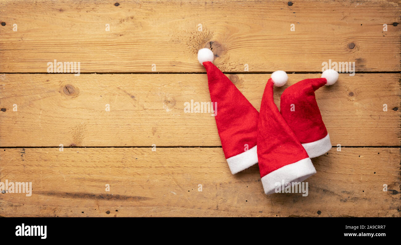 Una immagine di tre rossi Santa Claus cappelli con sfondo di legno Foto Stock