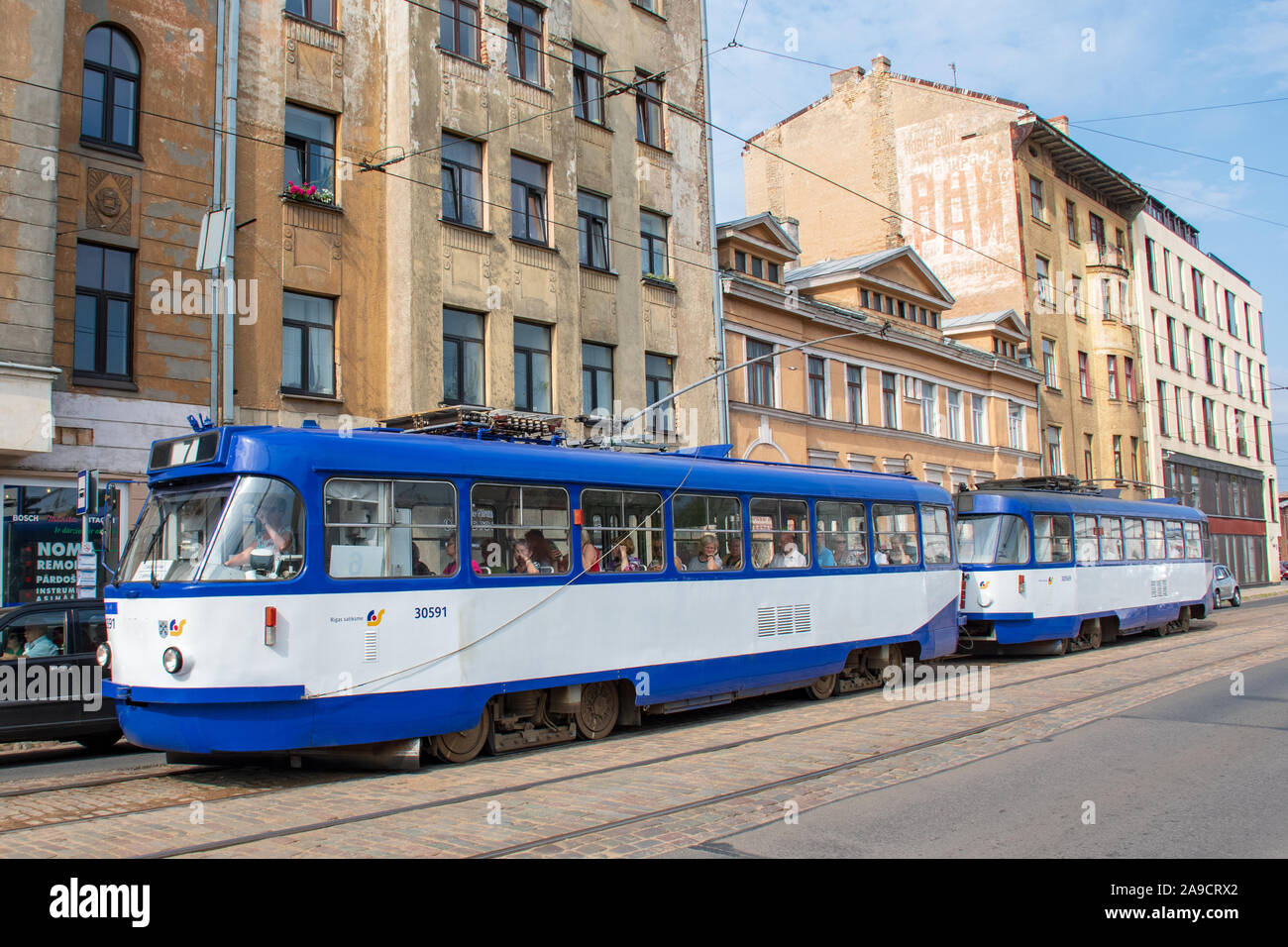 Era sovietica in Riga, Lettonia. Gli edifici di vecchia costruzione con scritti in cirillico, architettura sovietica con il vecchio tram in Riga Foto Stock