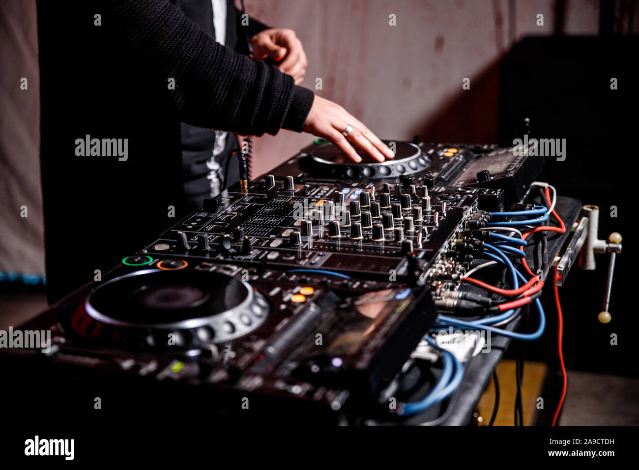 DJ suona live set e mixare la musica sulla console di piattaforma girevole nella fase nei night club. Disc Jokey le mani su un mixer audio station al club di partito. DJ Mixer Foto Stock