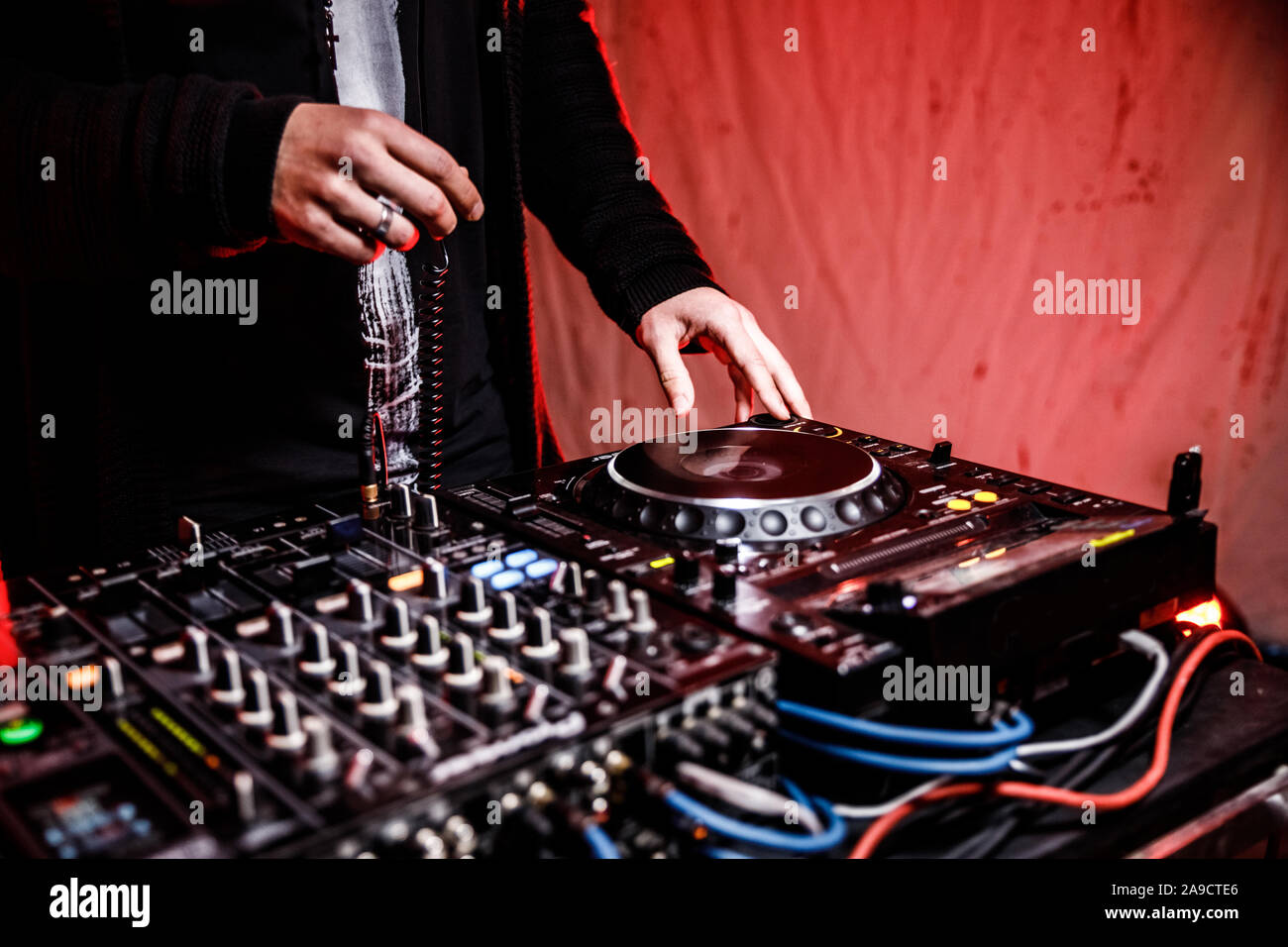 DJ suona live set e mixare la musica sulla console di piattaforma girevole nella fase nei night club. Disc Jokey le mani su un mixer audio station al club di partito. DJ Mixer Foto Stock