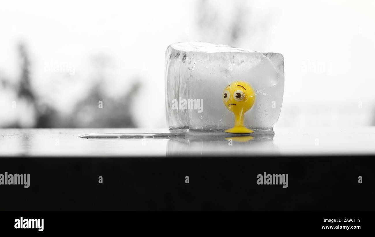 Gomma gialla toy smiley congelati in un cubo di ghiaccio in fusione di Sun Foto Stock