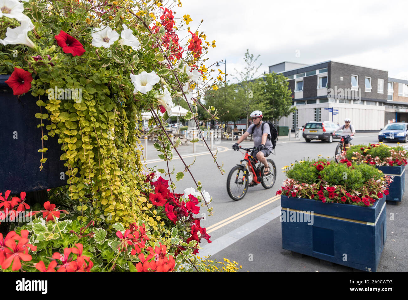 Cesti di fiori con i ciclisti in background, Abergavenny, Wales, Regno Unito Foto Stock