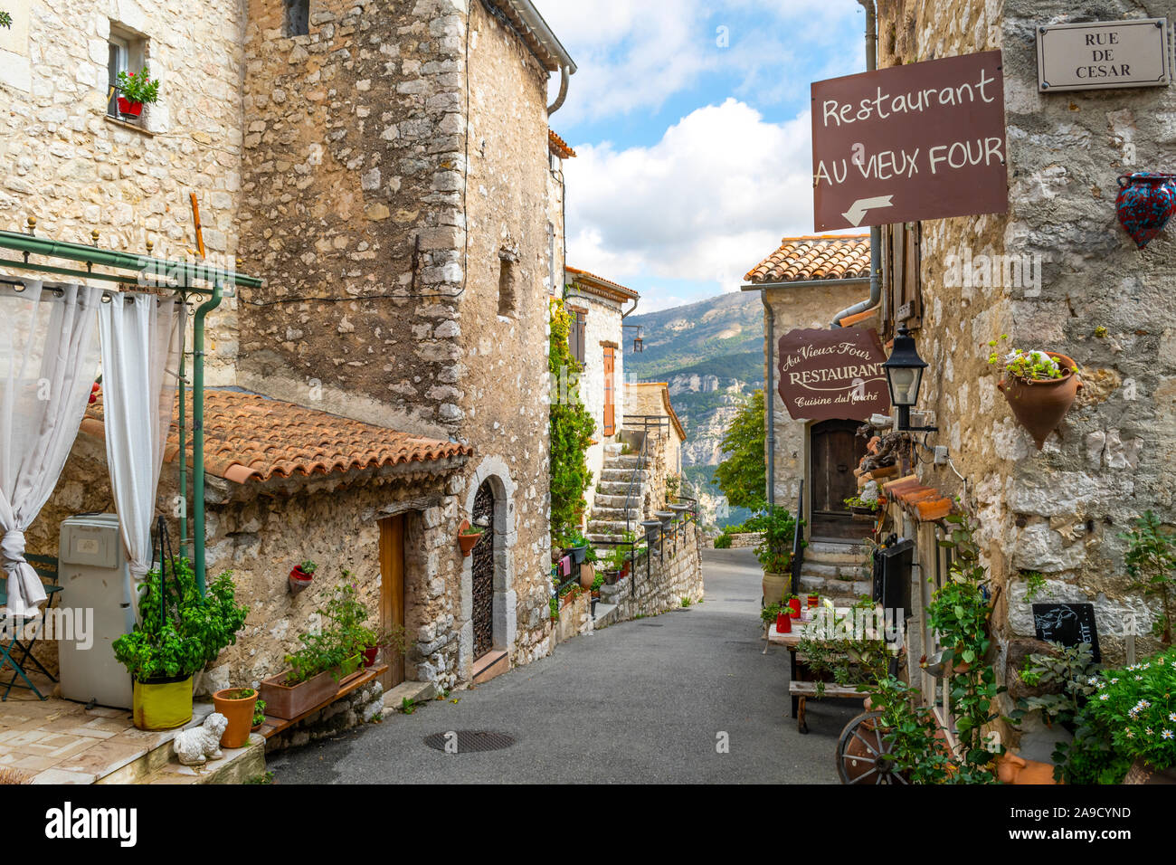 Un tipico pittoresca strada di negozi e caffè nel medioevo hilltop village di Gourdon, in zona Alpi Marittime della Riviera Francese. Foto Stock