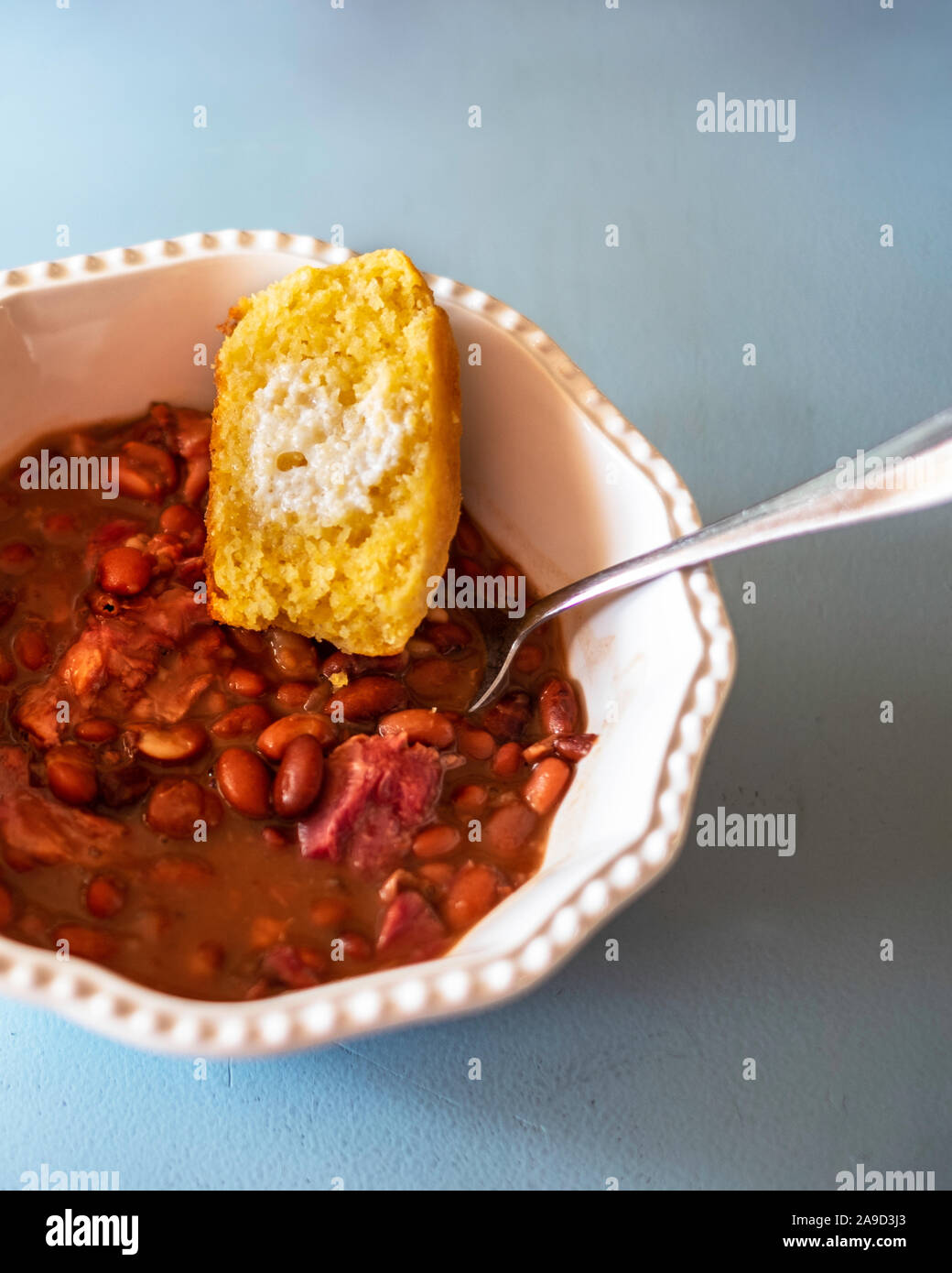 Cuocere i fagioli pinto con garretto e cornbread in una ciotola bianco. Closeup, overhead. Foto Stock