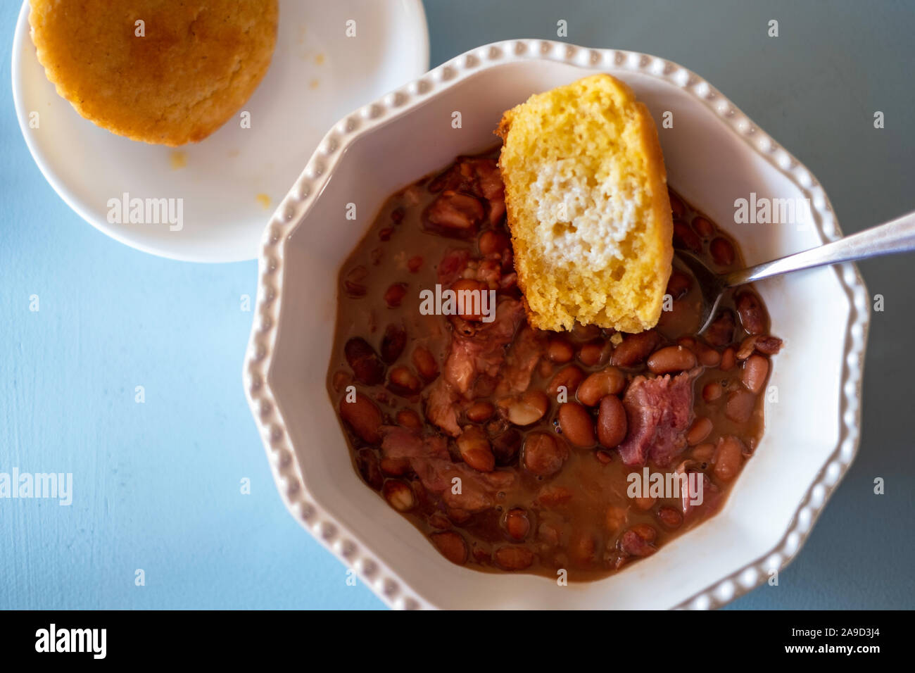 Cuocere i fagioli pinto con garretto e cornbread in una ciotola bianco. Closeup, overhead. Foto Stock