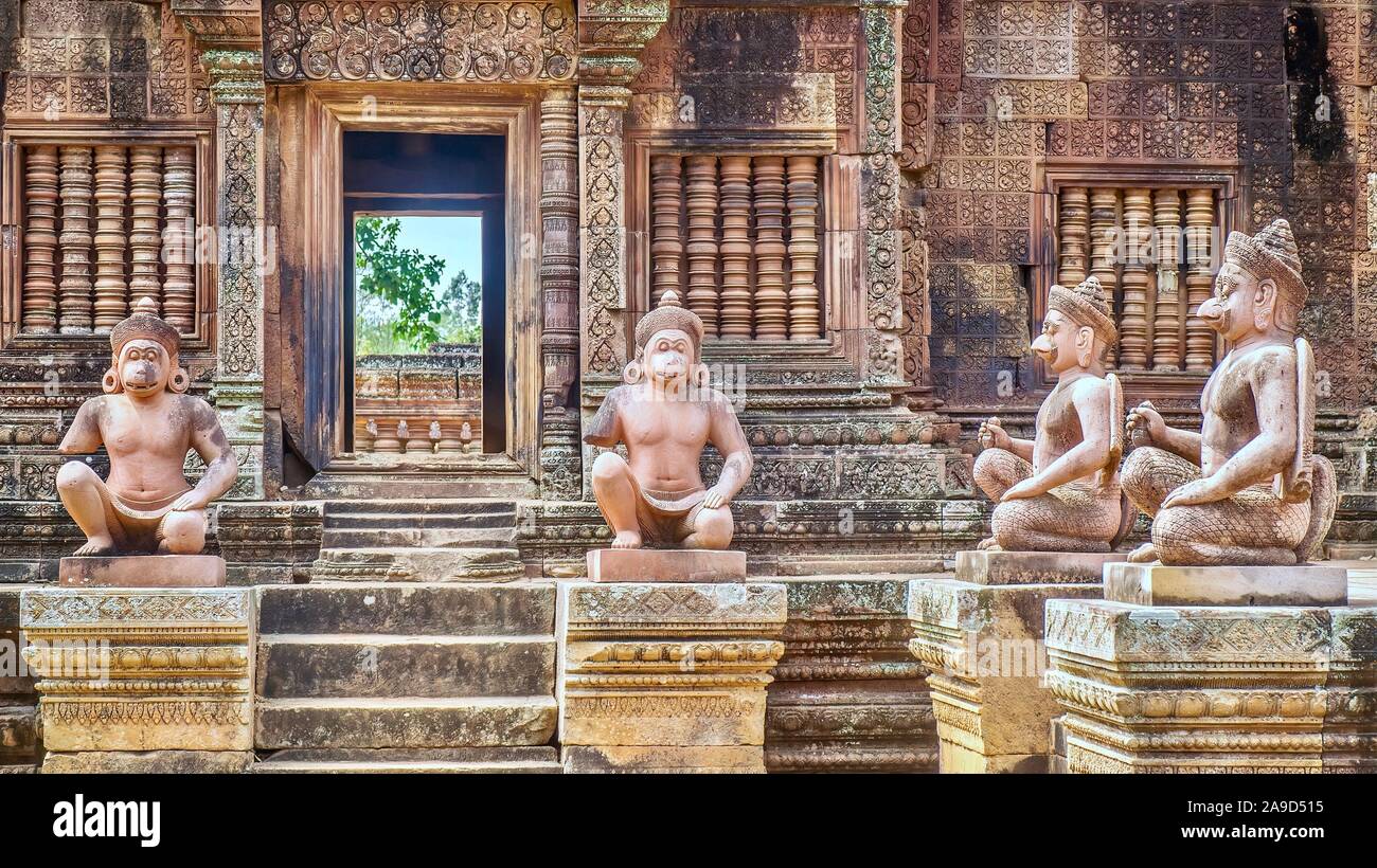 Statue di figure umane con teste di animali all'ingresso del decimo secolo il Banteay Srei tempio di Angkor Wat in Siem Reap, Cambogia. Foto Stock