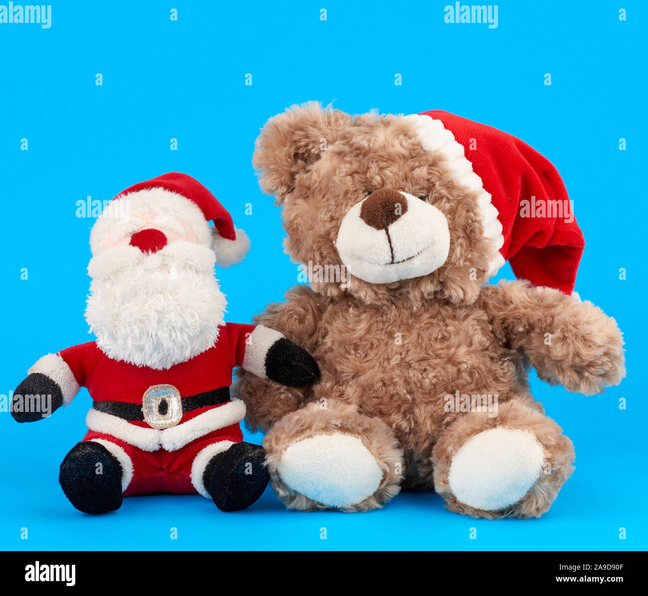Piccolo orsacchiotto in Red Hat di Natale e Babbo Natale su sfondo blu Foto Stock