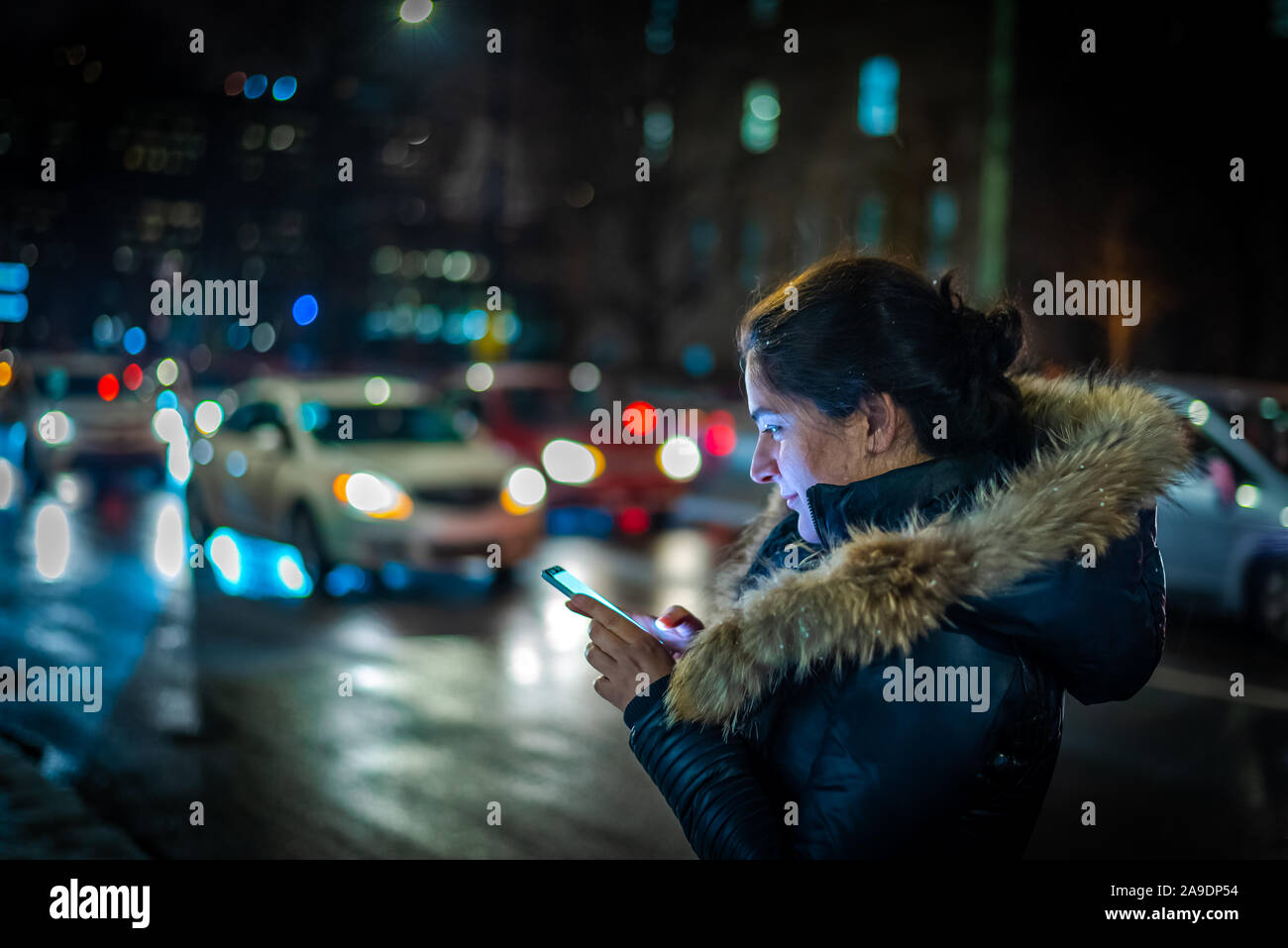 Donna che cammina e i messaggi di testo in una strada di città di notte Foto Stock