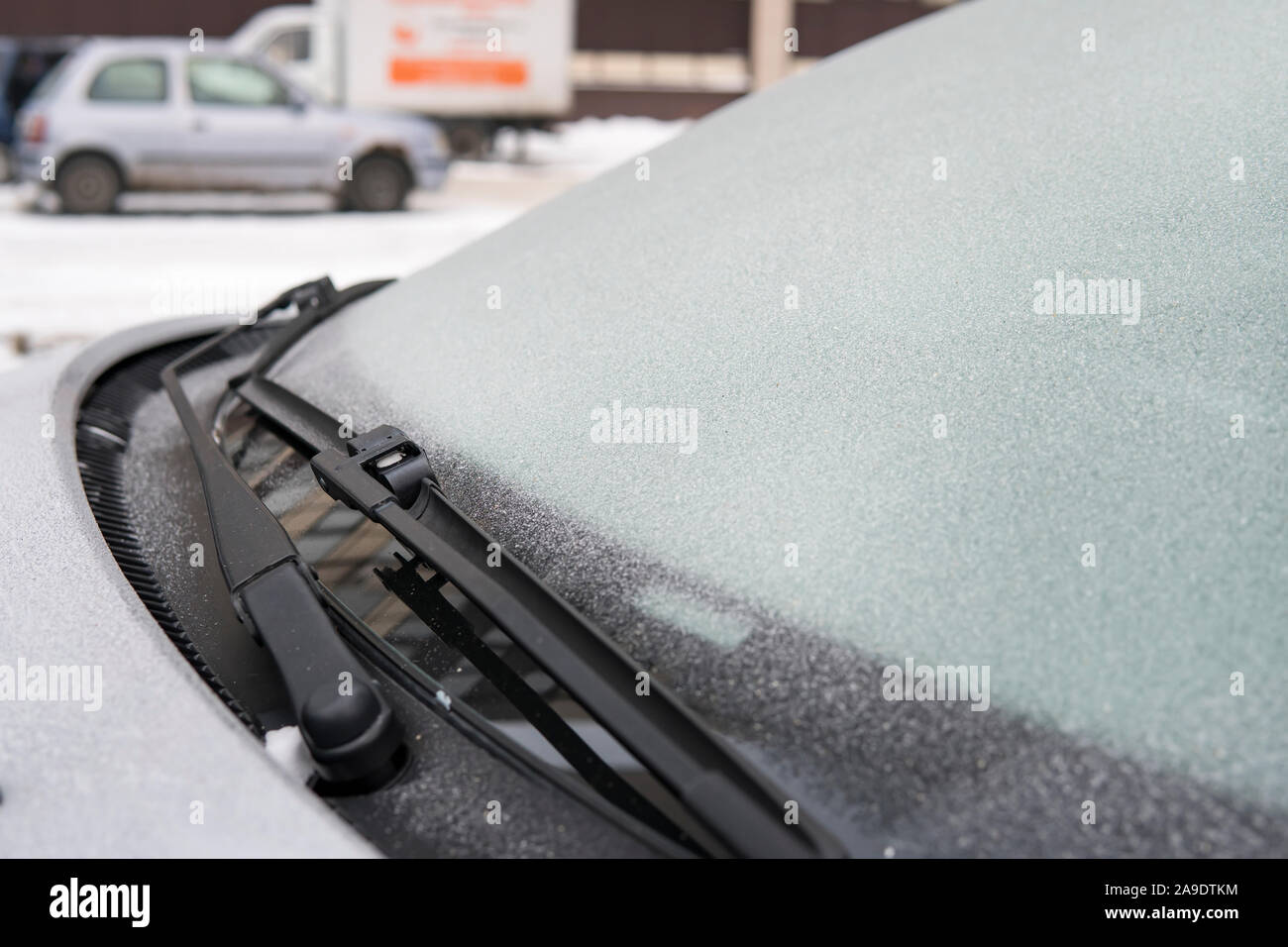 Fiocchi di neve ghiacciata su frosty auto in freddo. tergicristallo su un auto. auto bidello si è bloccato al vetro della vettura a bassa temperatura. Problemi con auto in Foto Stock