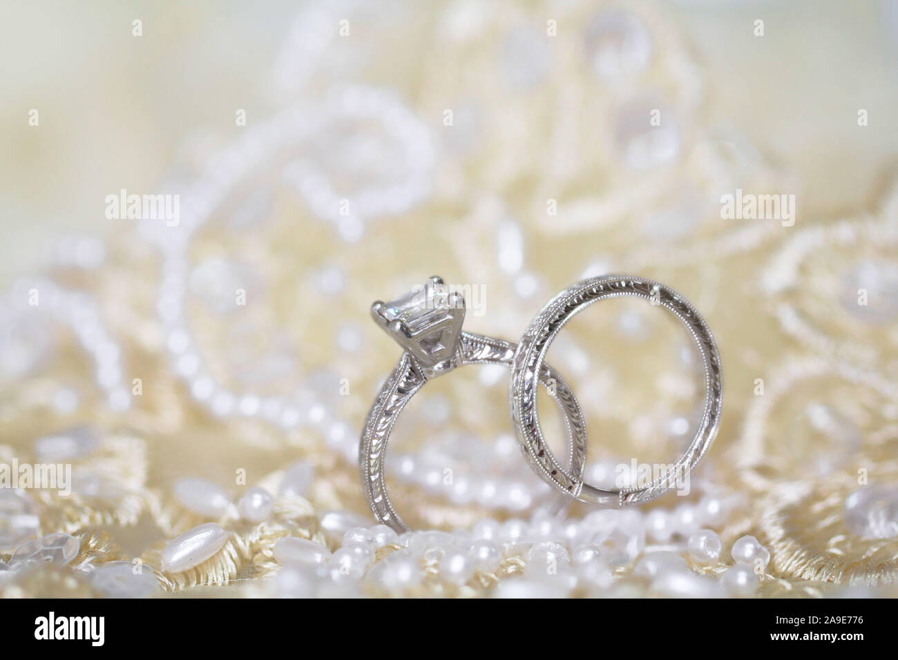 Nozze di diamante e gli anelli di fidanzamento su una perla sfondo pizzo Foto Stock