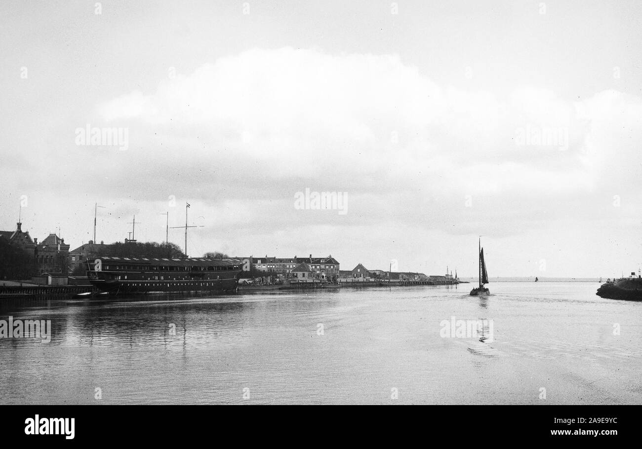 Una barca da pesca lascia il porto con la nave di guardia sulla sinistra e Fort Harssens sulla destra Foto Stock