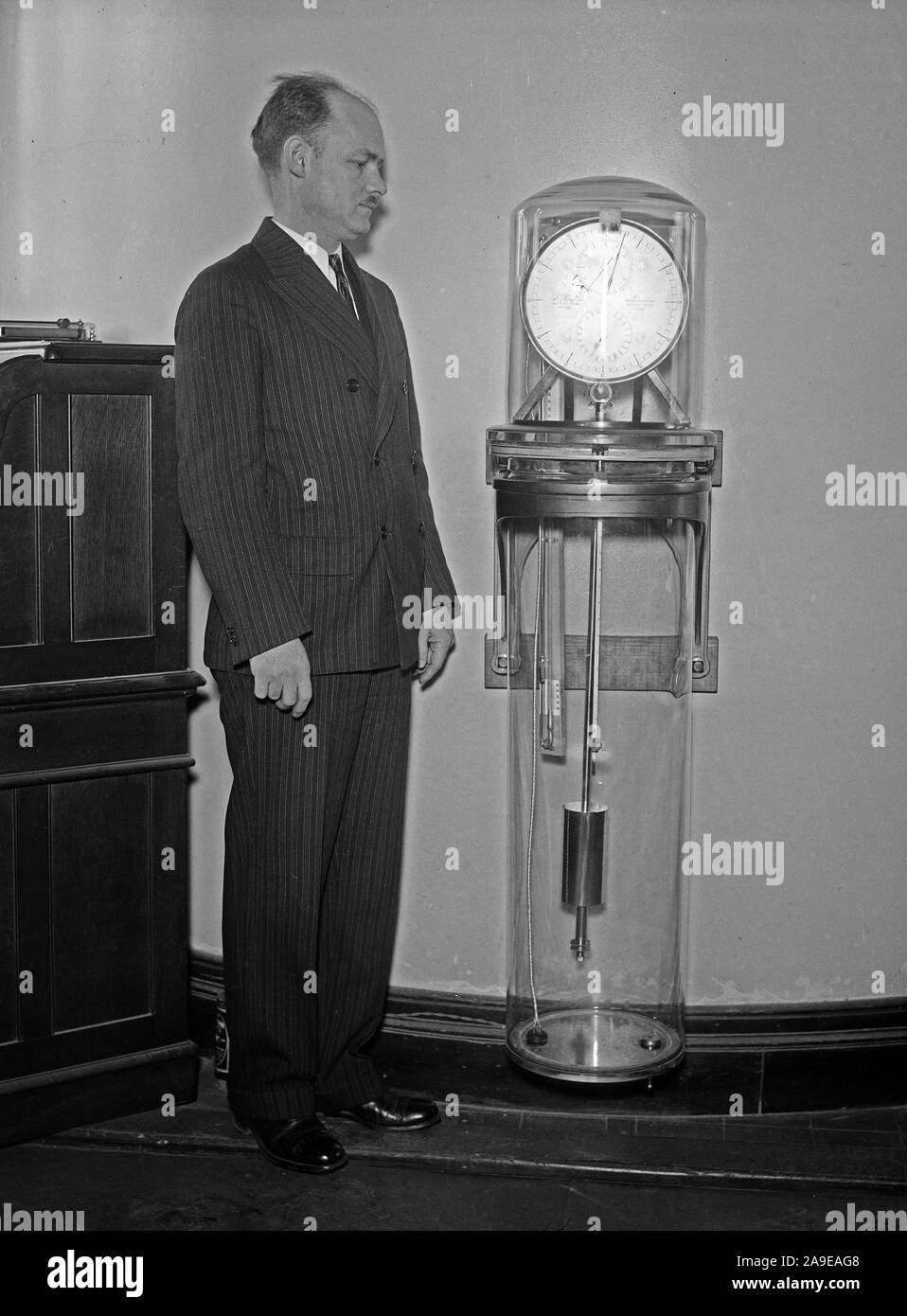 Uomo con un Riefler orologio a pendolo, lo standard principale per intervallo di tempo misure dal 1904 al 1929 ca. 1931 Foto Stock