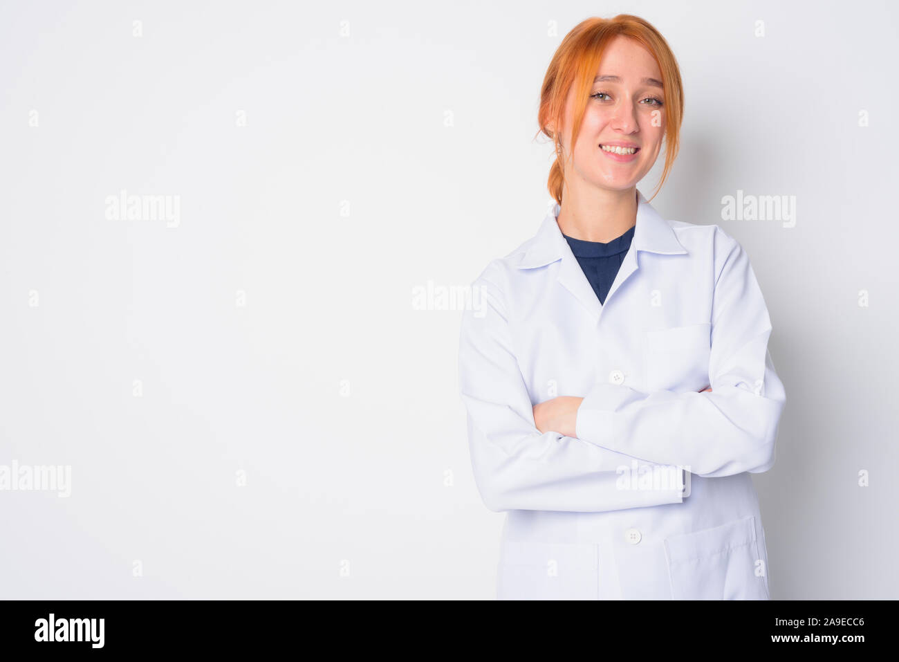 Ritratto di felice giovane bella redhead medico donna sorridente con le braccia incrociate Foto Stock