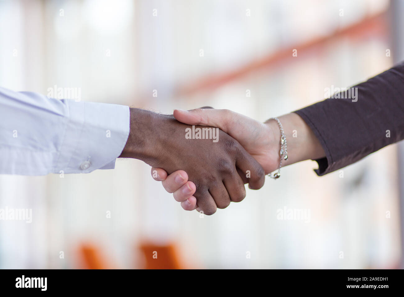 Stretta di mano tra africani e di un uomo caucasico. Foto Stock
