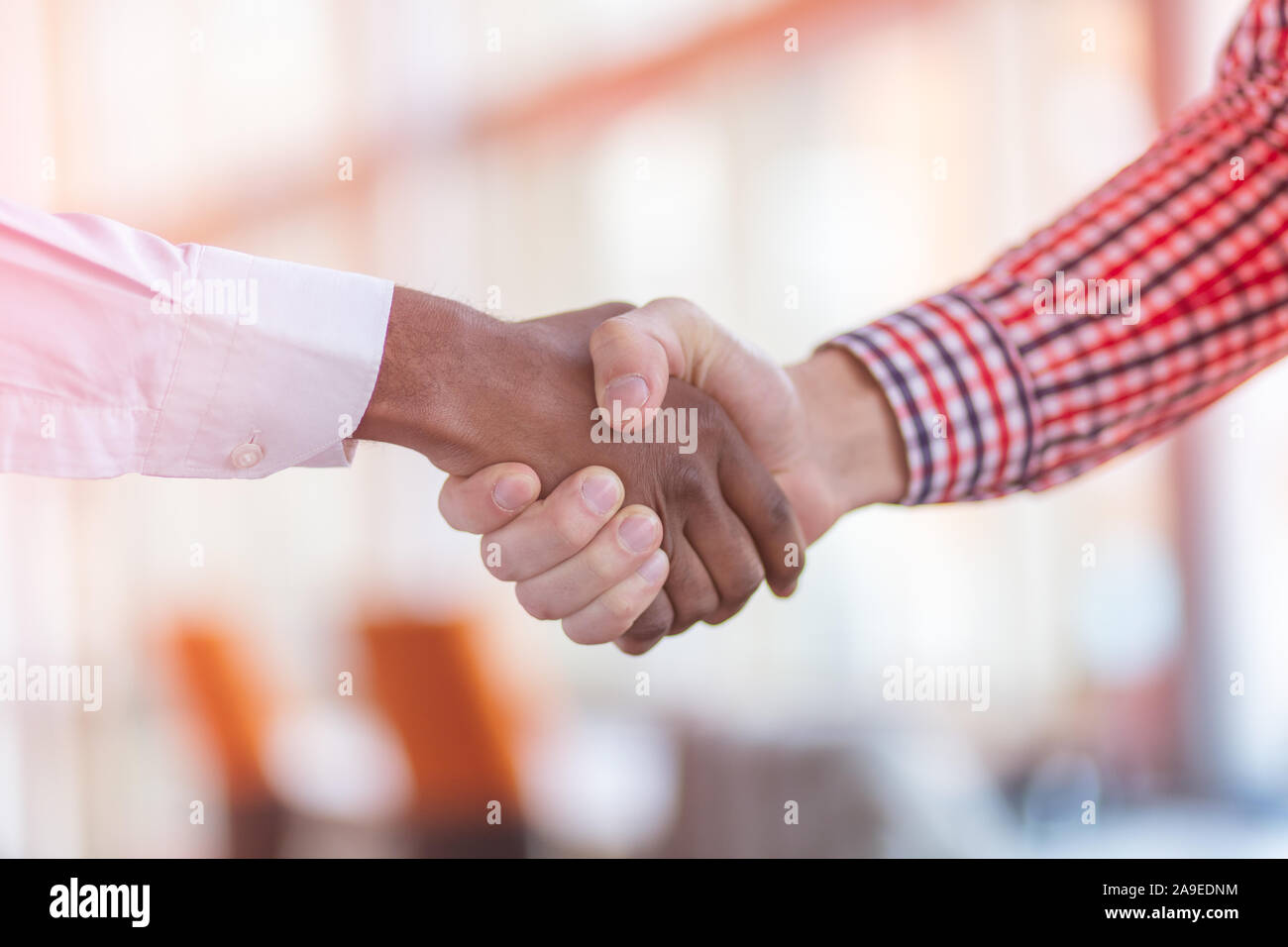 Stretta di mano tra africani e di un uomo caucasico. Foto Stock