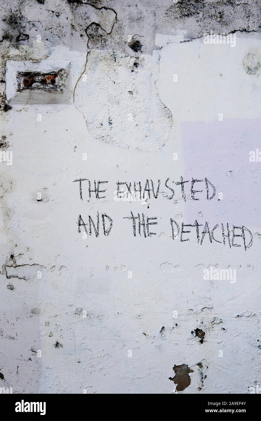 Le parole l'esausto e il distaccato scritto in matita su UNA parete bianca distressed e Weathered Foto Stock