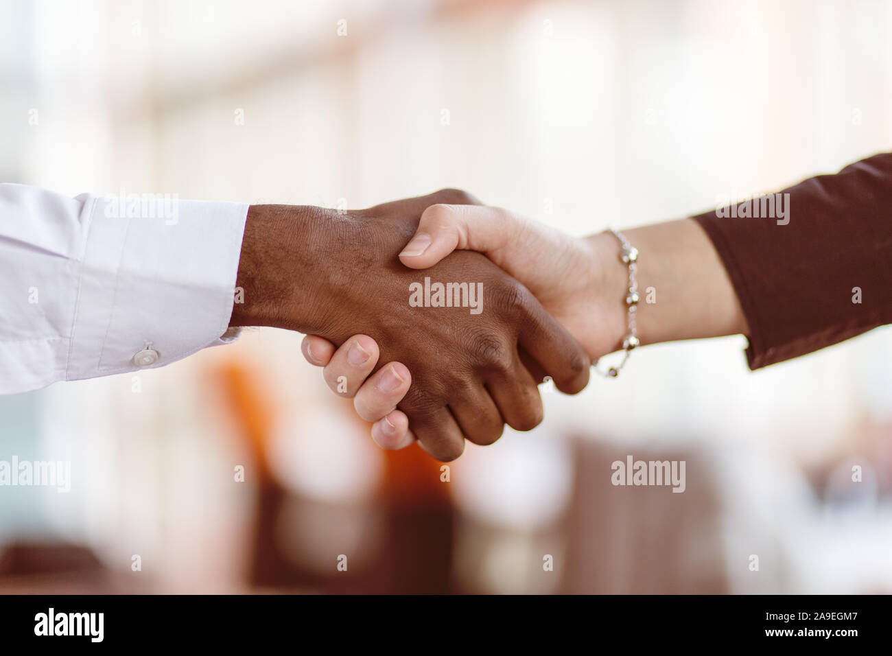 Stretta di mano tra africani e di un uomo caucasico. Foto Stock