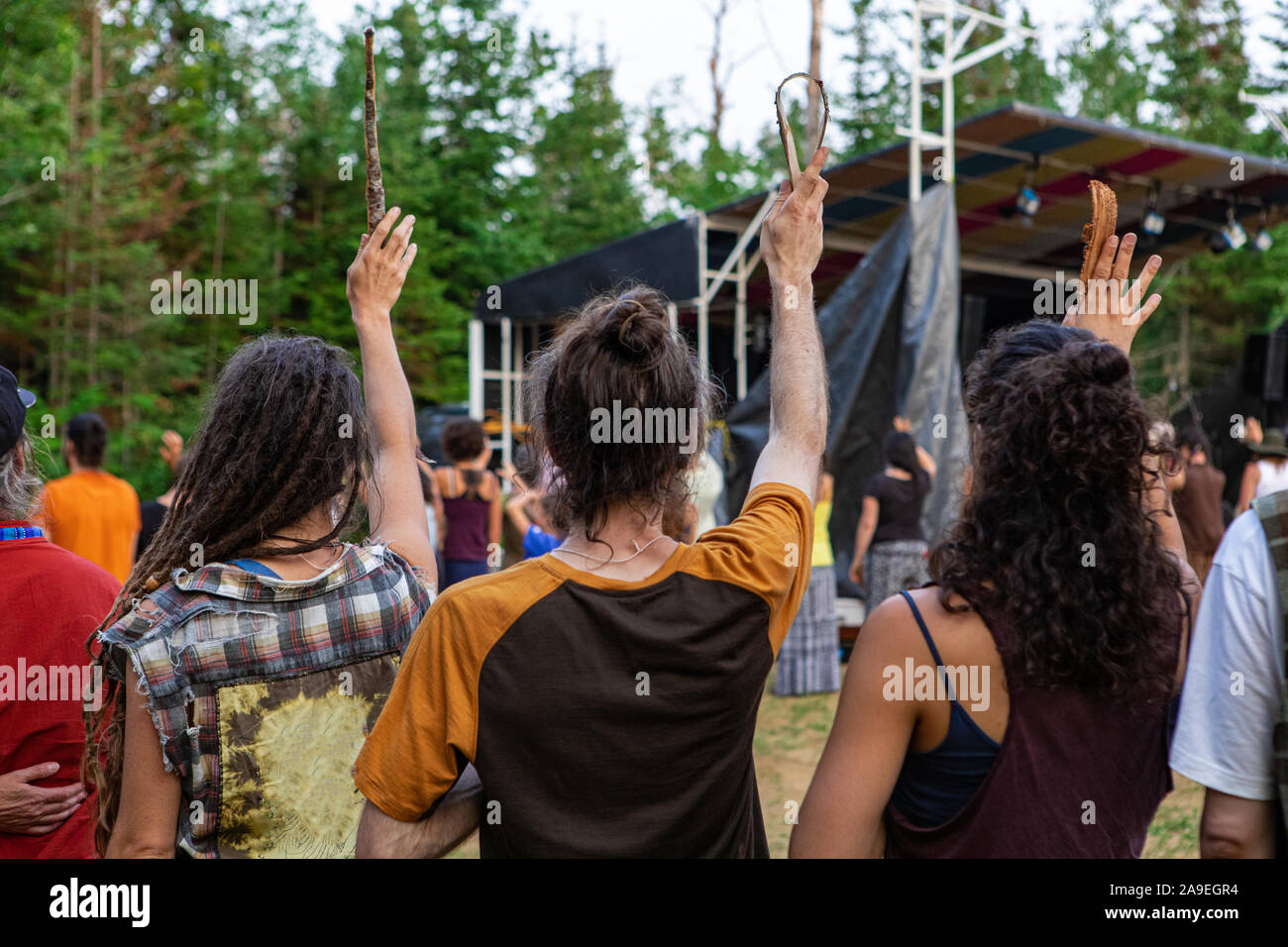 Diverse persone godono di appuntamento spirituale, il gruppo di individui in piedi con le braccia alzate in aria come si pratica sciamanica e tradizioni native in foresta Foto Stock