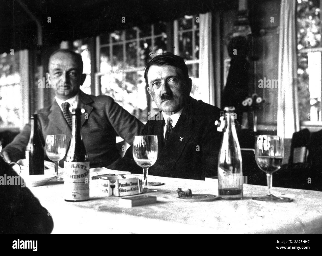 Adolf Hitler seduta a tavola con bottiglie di vino sul tavolo Foto Stock
