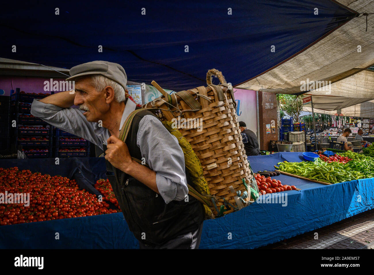 Uomo che porta un cestello nel mercato di Fatih, Istanbul, Turchia Foto Stock