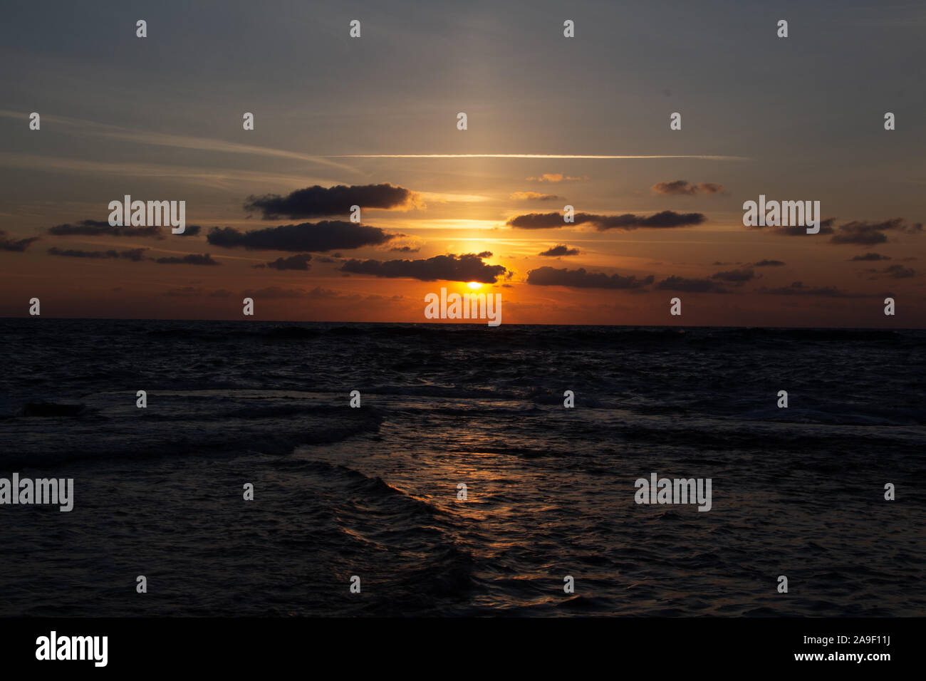 Godendo l'ultima luce del giorno con la fantastica vista del mare e i colori del tramonto rendono nel cielo Foto Stock