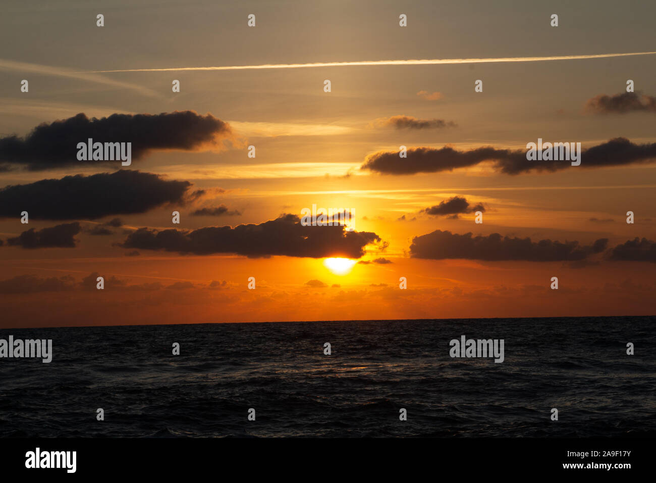 Godendo l'ultima luce del giorno con la fantastica vista del mare e i colori del tramonto rendono nel cielo Foto Stock