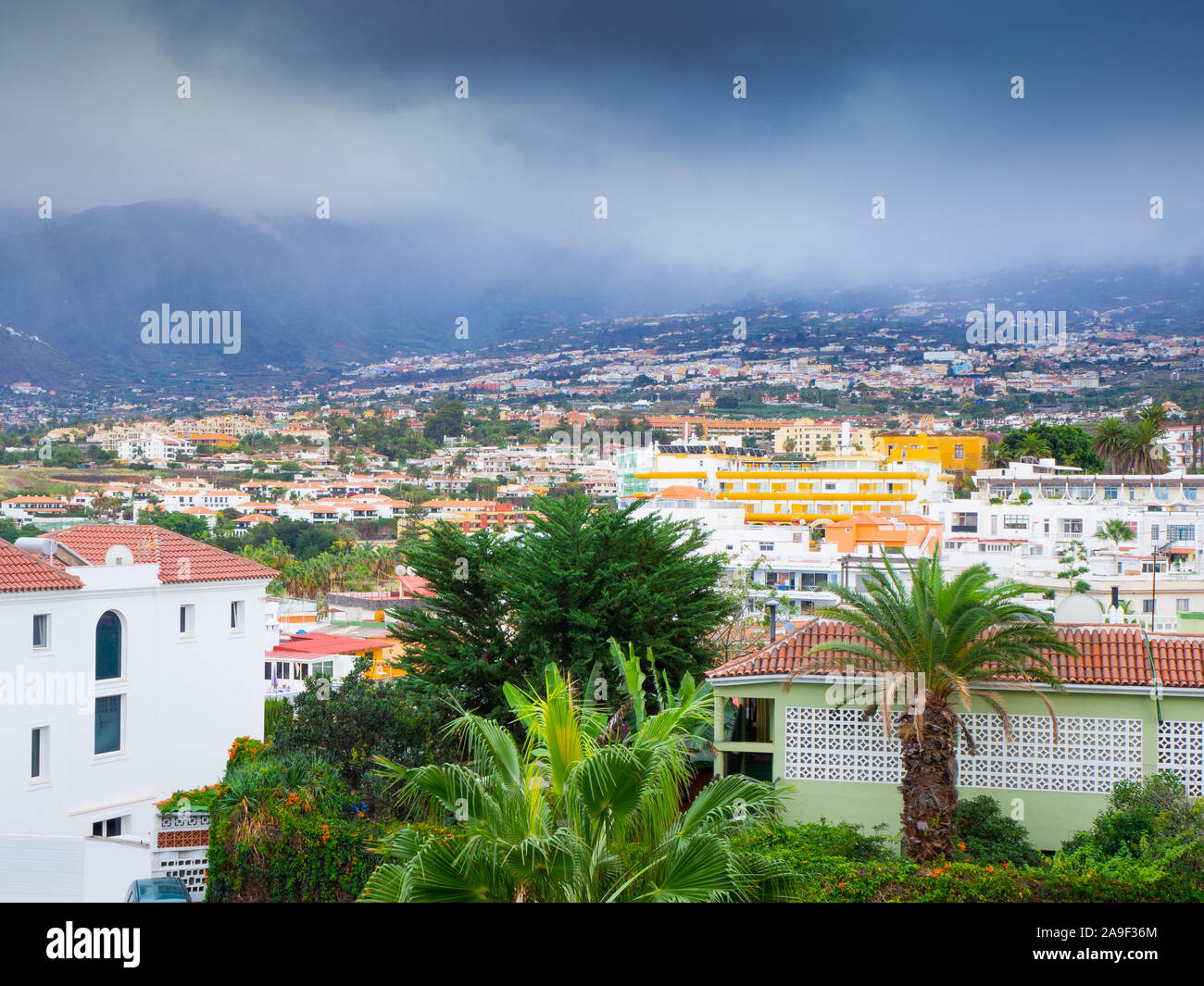 Vista panoramica sui tetti della città e il cloud colline coperte a Puerto de la Cruz, Tenerife, Isole Canarie Foto Stock