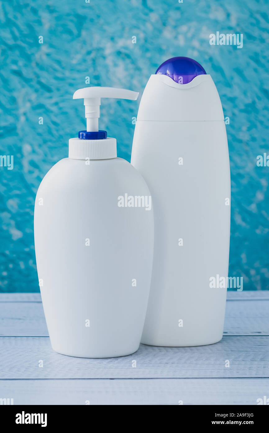 Due bianchi di bottiglie in plastica su sfondo blu. Concetto igienico. Un gruppo di contenitori puliti su sfondo turchese. Foto Stock
