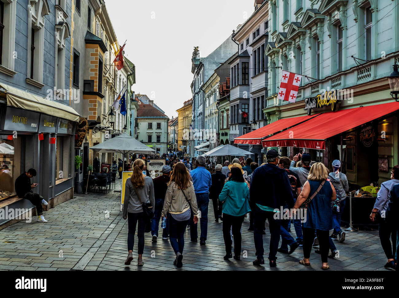 La gente a passeggiare nella città vecchia, la strada dello shopping di Bratislava, portando al XVII secolo la chiesa e il Monastero dei fratelli misericordioso Foto Stock