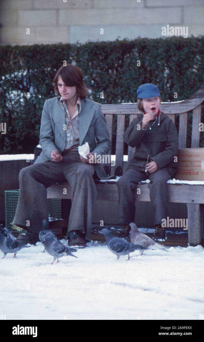 1973 due giovani seduti sulla panchina di neve, Leeds, West Yorkshire, Regno Unito Foto Stock