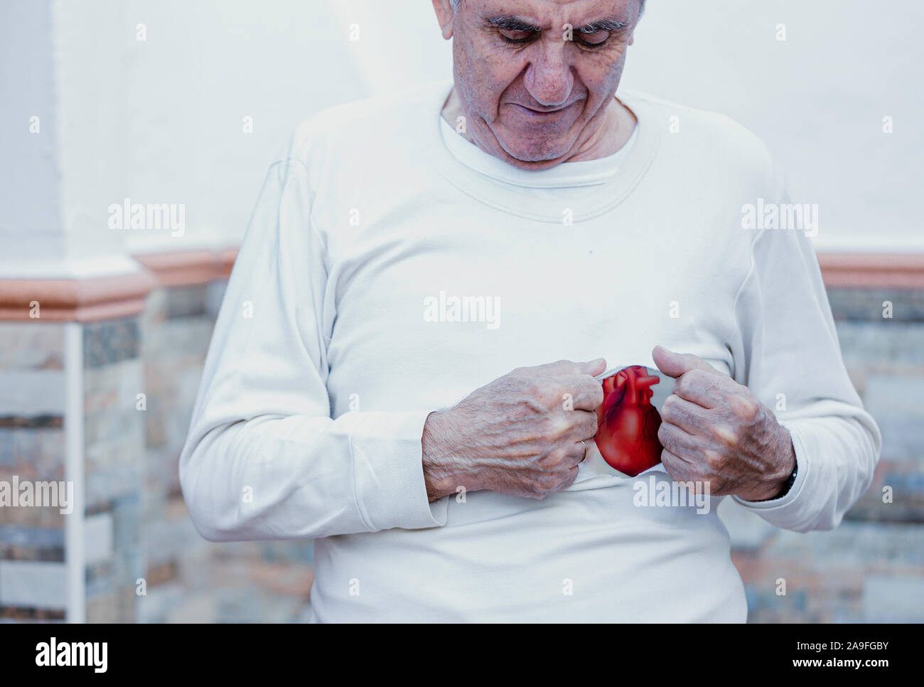 Senior maschili che mostra cuore rosso. La cura della salute, sana con esercizio e sano buon inizio giornata mondiale del cuore Foto Stock