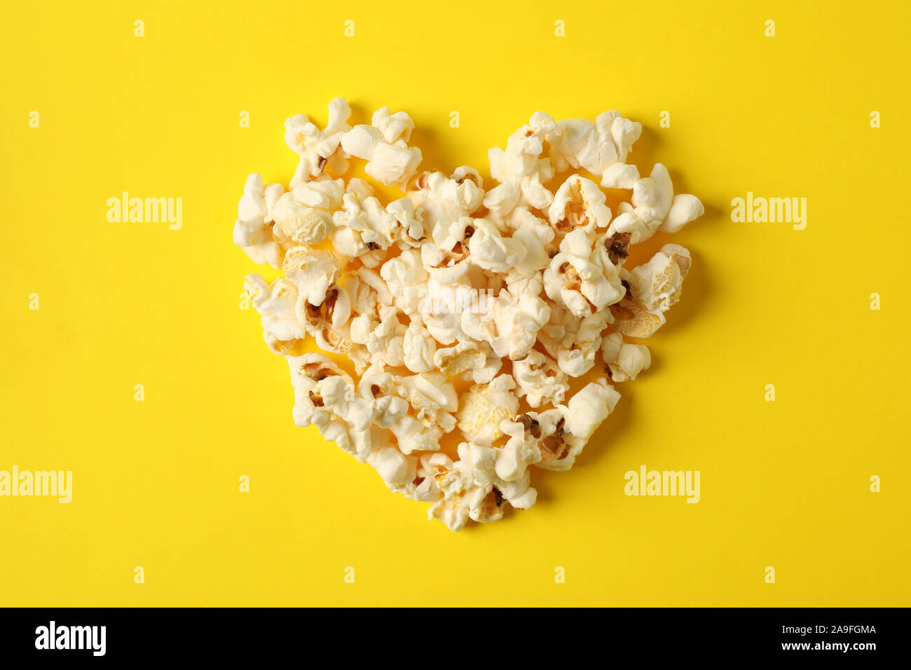 Piano di composizione dei laici con popcorn cuore su sfondo giallo, spazio per il testo Foto Stock