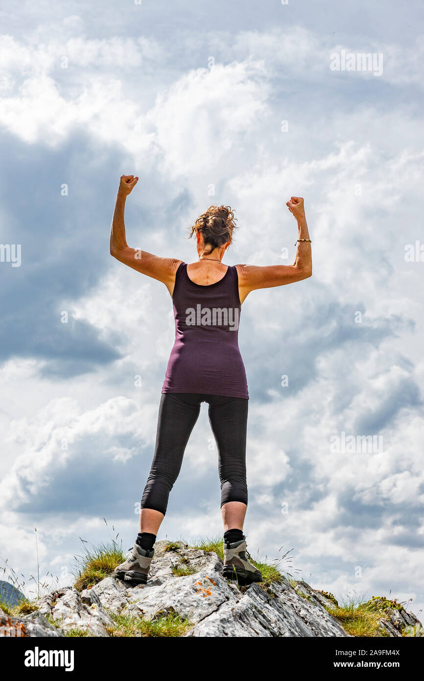 Donna in posa di vittoria su un picco di montagna Foto Stock