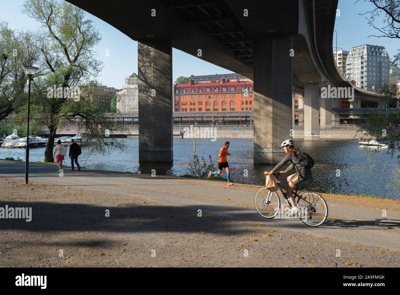 Kungsholmen Stoccolma, vista in estate del popolo svedese in esecuzione e in bicicletta al di sotto del ponte Barnhusbron nel Kungsholms Strand park, Stoccolma. Foto Stock