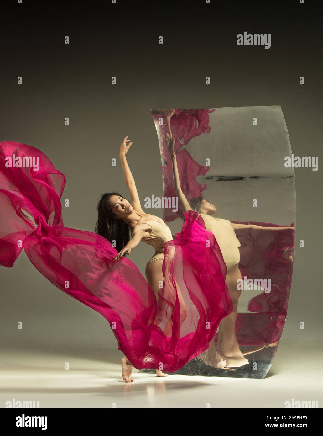 La danza con il fuoco. Balletto moderno ballerina sullo sfondo marrone con  specchio. Illusione riflessioni sulla superficie. Magia di flessibilità,  movimento con il tessuto. Concetto di arte creativa dancing, azione  stimolante Foto