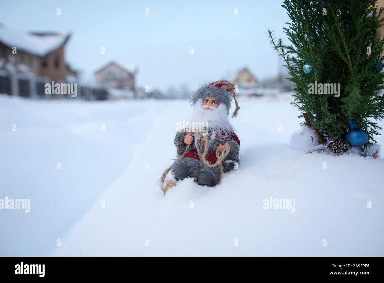 Santa sulla slitta nel bianco della neve nei pressi di case di villaggio Foto Stock