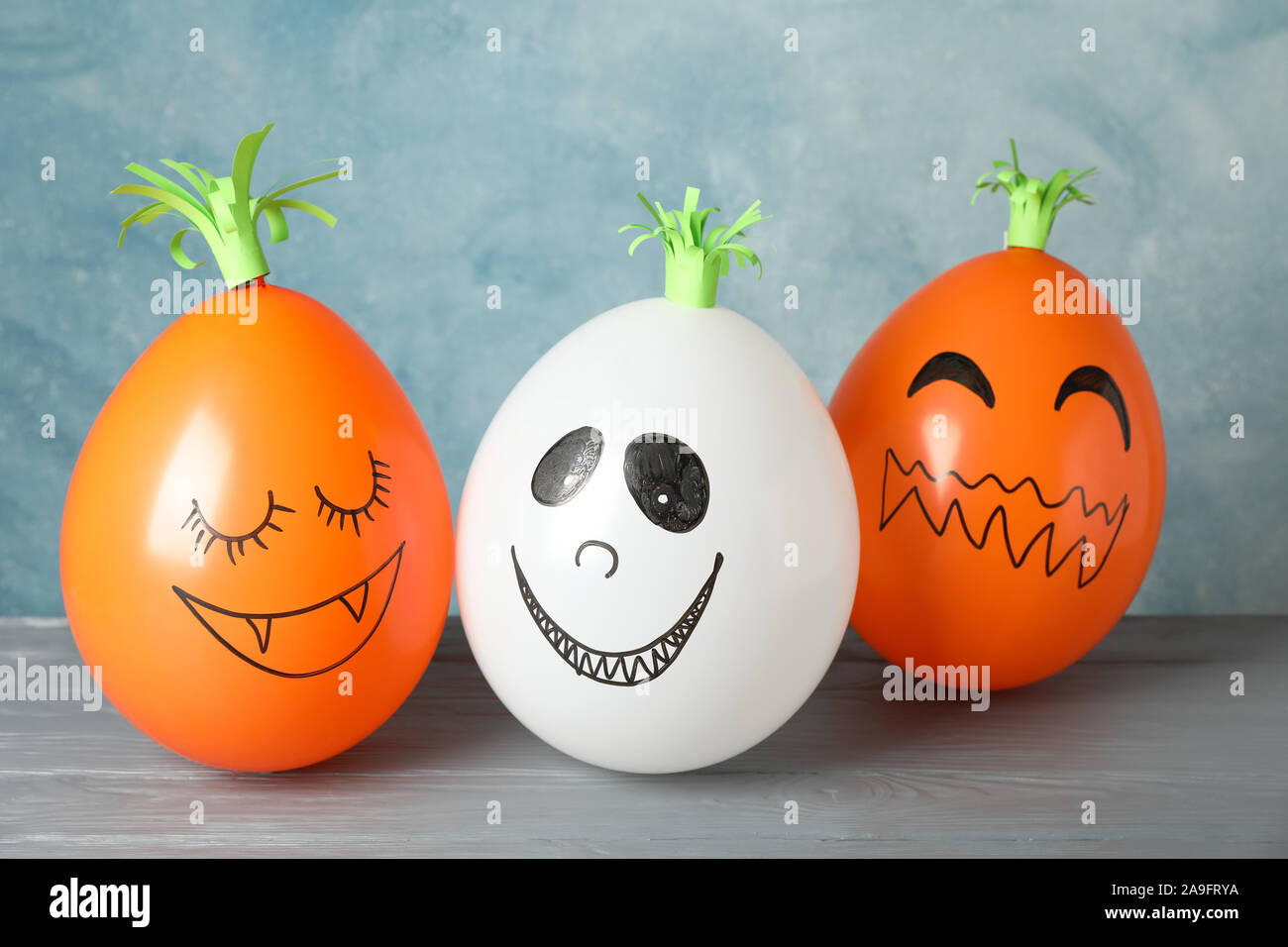 Zucche divertenti su legno grigio Sfondo, spazio per il testo Foto Stock