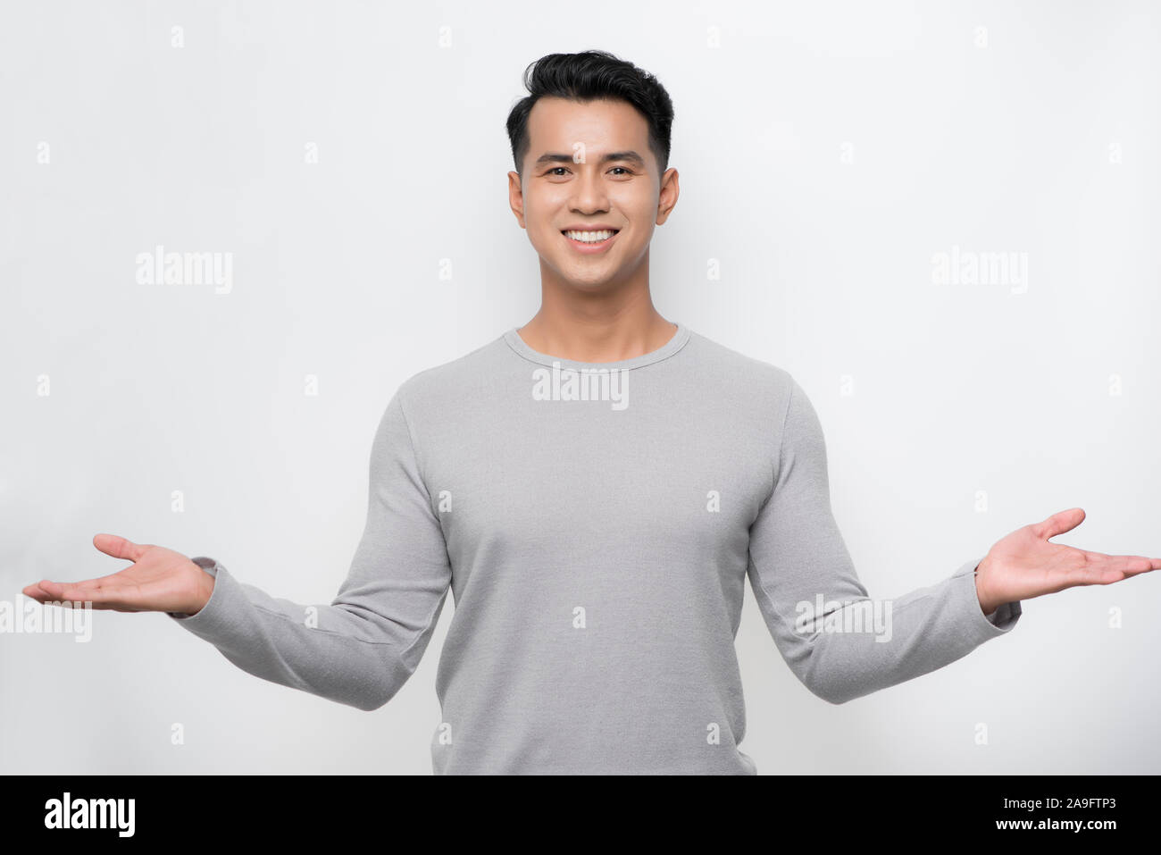 Felice giovane uomo asiatico celebra con due mani in aria sulla isolare lo sfondo bianco. Foto Stock