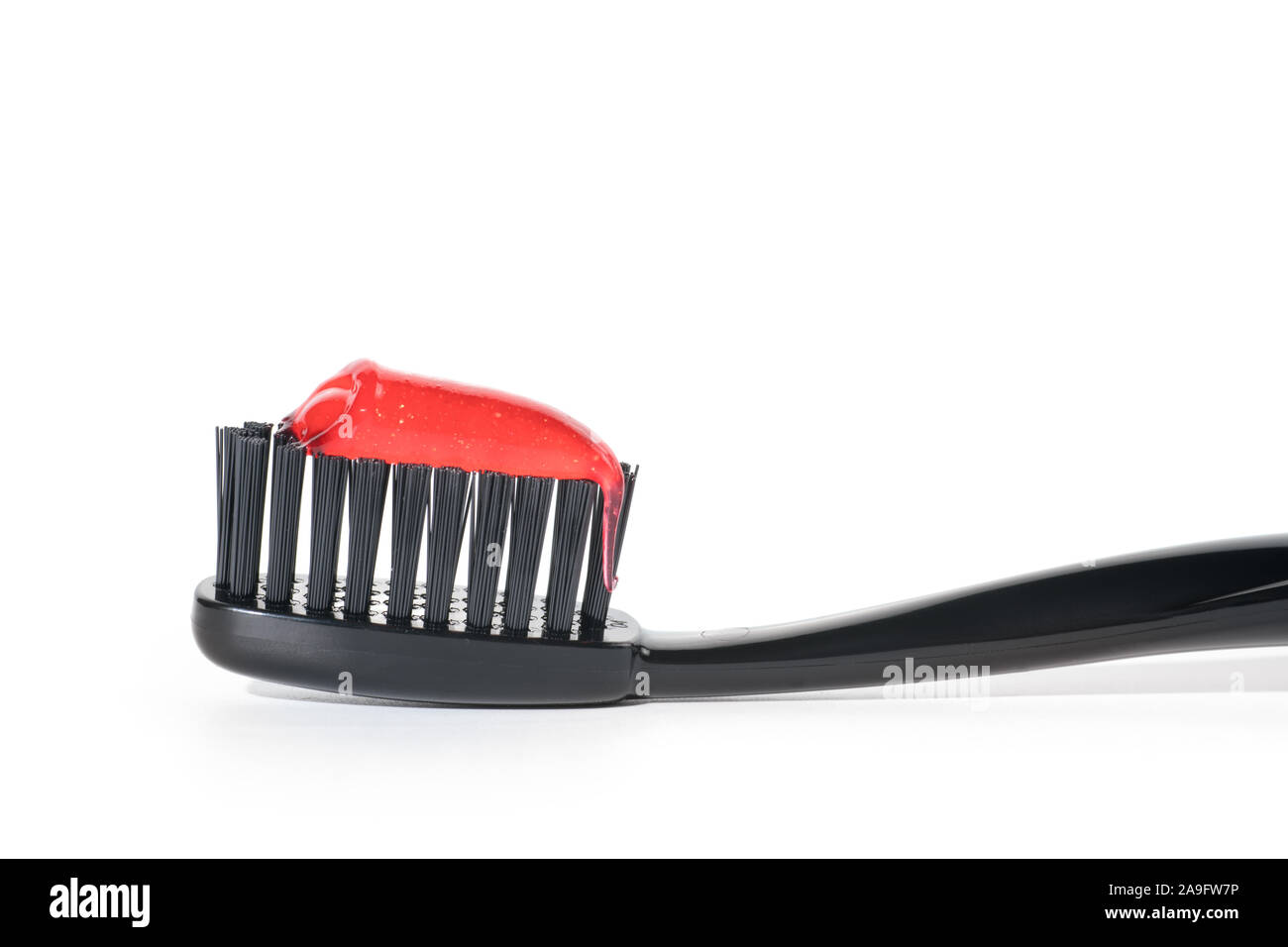 Spazzolino da denti nero con rosso dentifricio close up, isolato su sfondo bianco Foto Stock