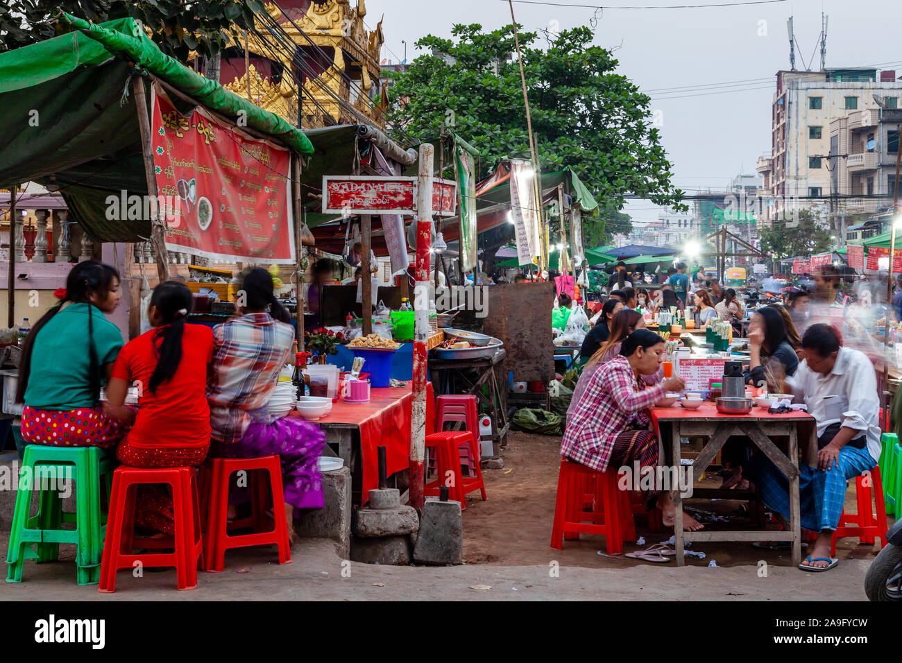 La popolazione locale strada mangiando cibo al mercato notturno, Mandalay Myanmar. Foto Stock