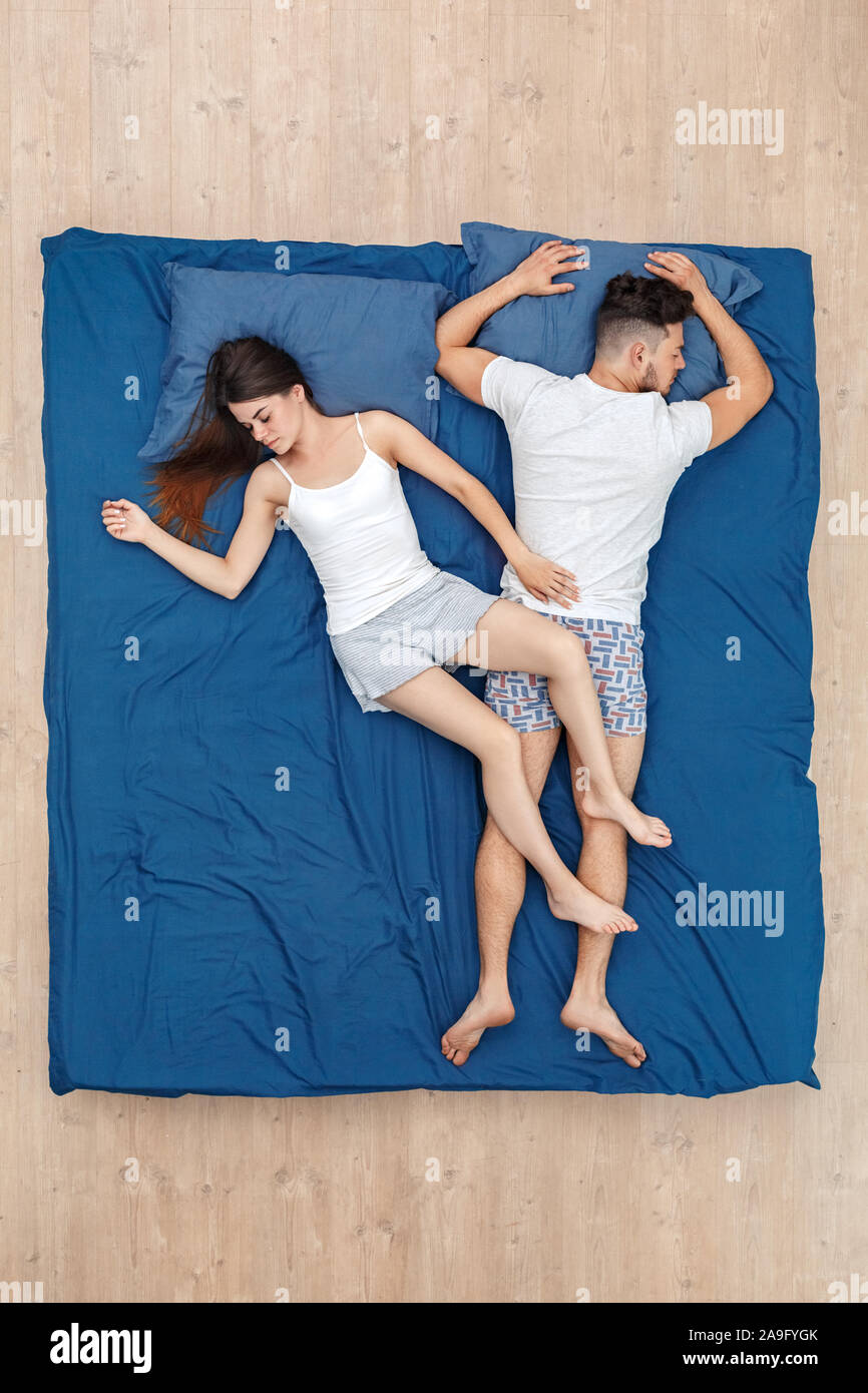 Andare a dormire. Coppia giovane che dorme sul letto vista superiore donna mettendo le gambe sull'uomo Foto Stock