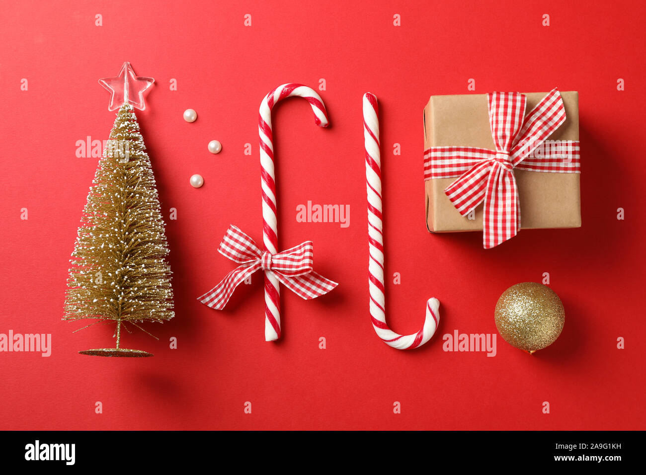 Candy canne e accessori di natale su sfondo rosso, lo spazio per il testo Foto Stock