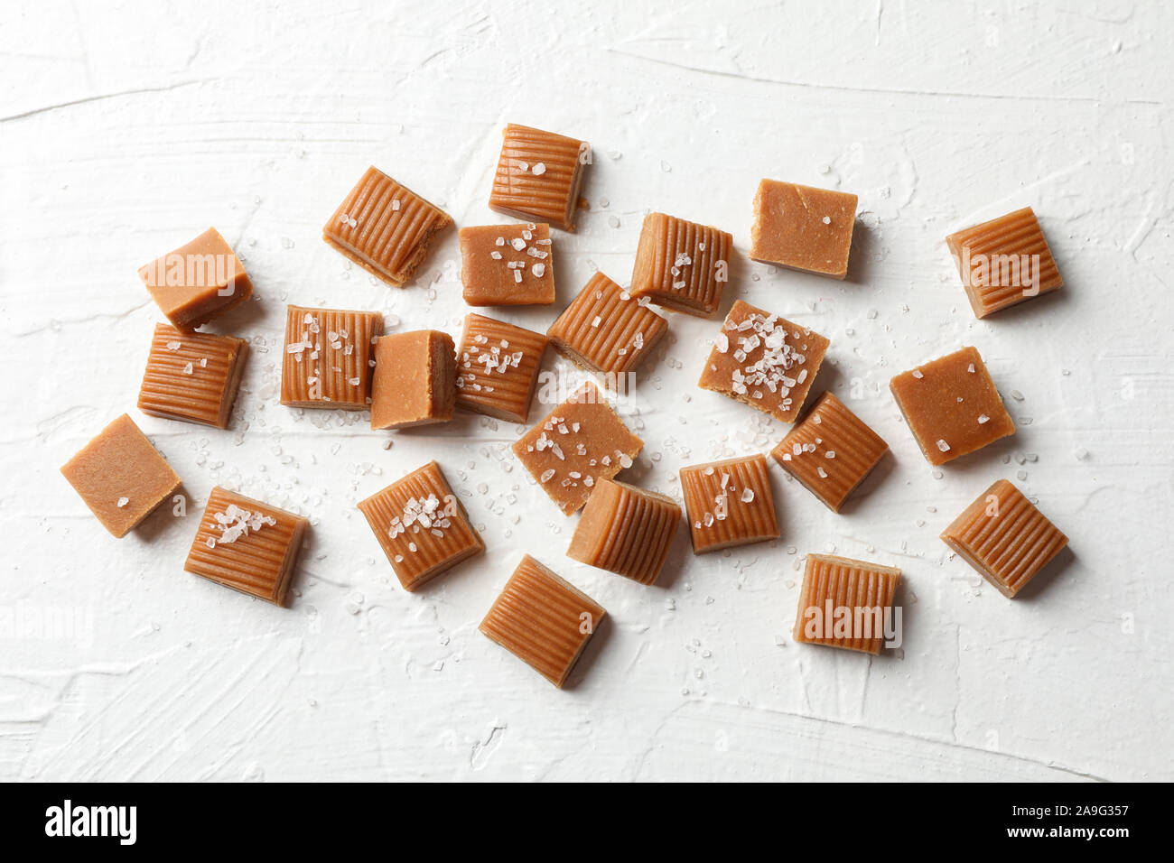 Salate caramello caramelle sul cemento bianco sfondo, spazio per il testo Foto Stock
