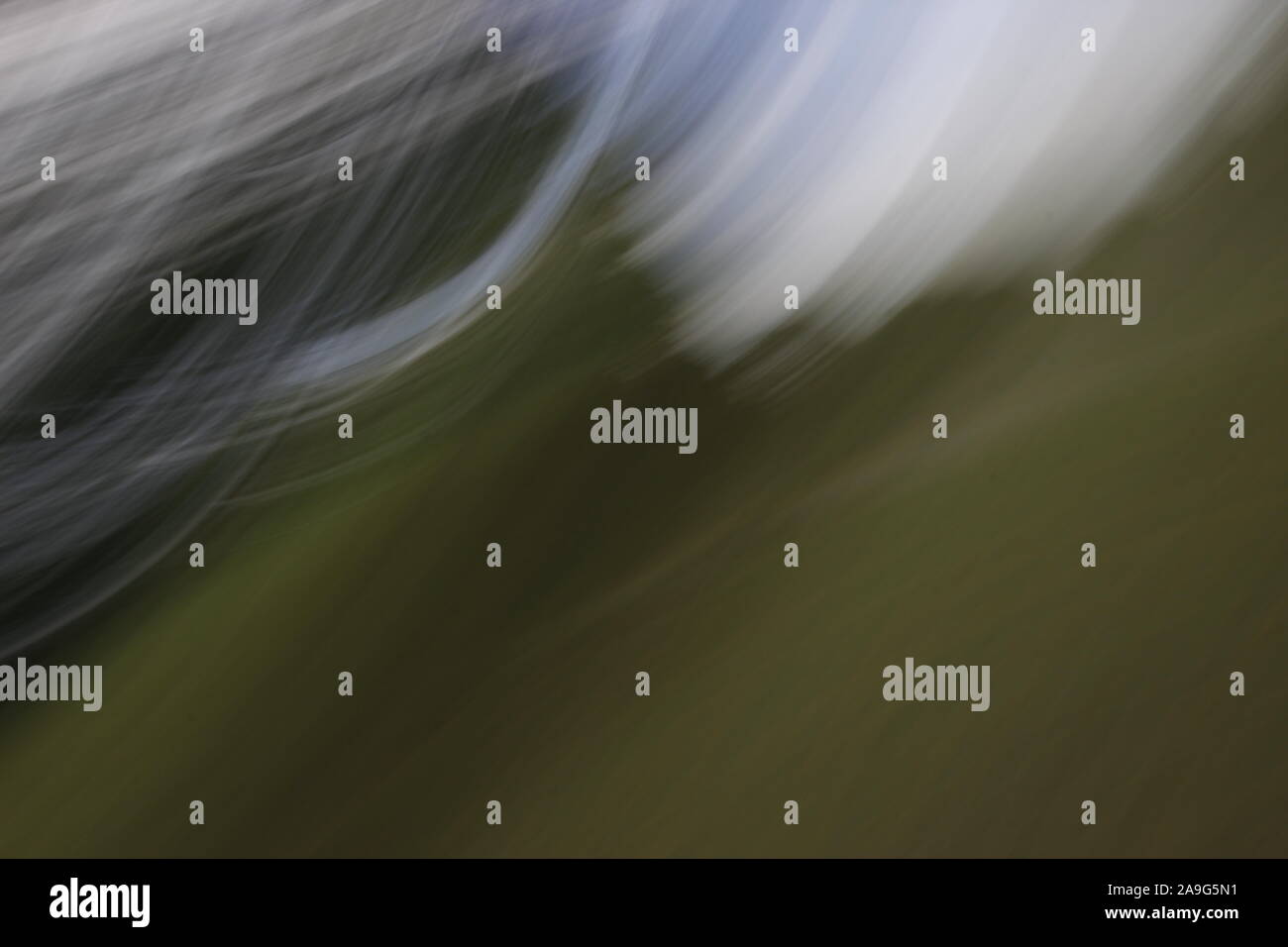 Immagine astratta che mostra striature sfocate di luce bianca o di colore contro sfumature di verde in background Foto Stock