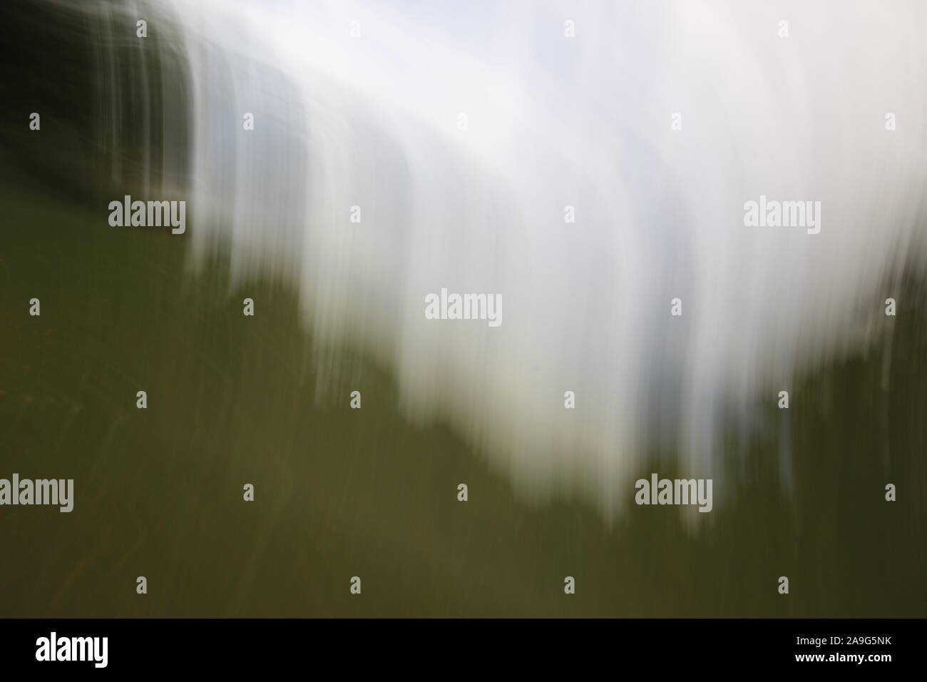 Immagine astratta che mostra striature sfocate di luce bianca o di colore contro sfumature di verde in background Foto Stock