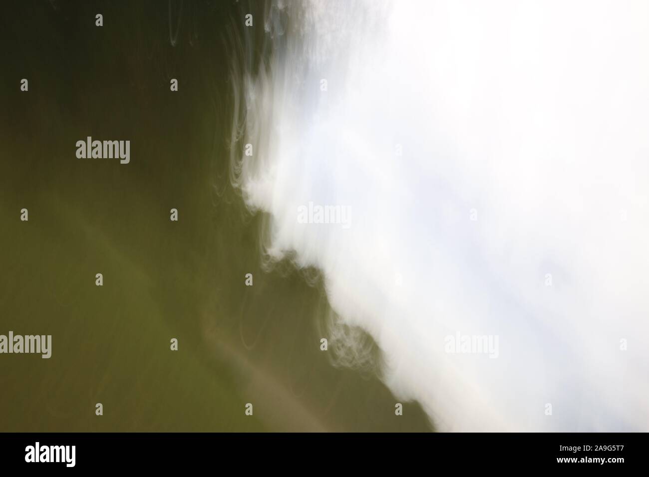 Immagine astratta che mostra striature sfocate di luce bianca o di colore contro sfumature di verde in background Foto Stock