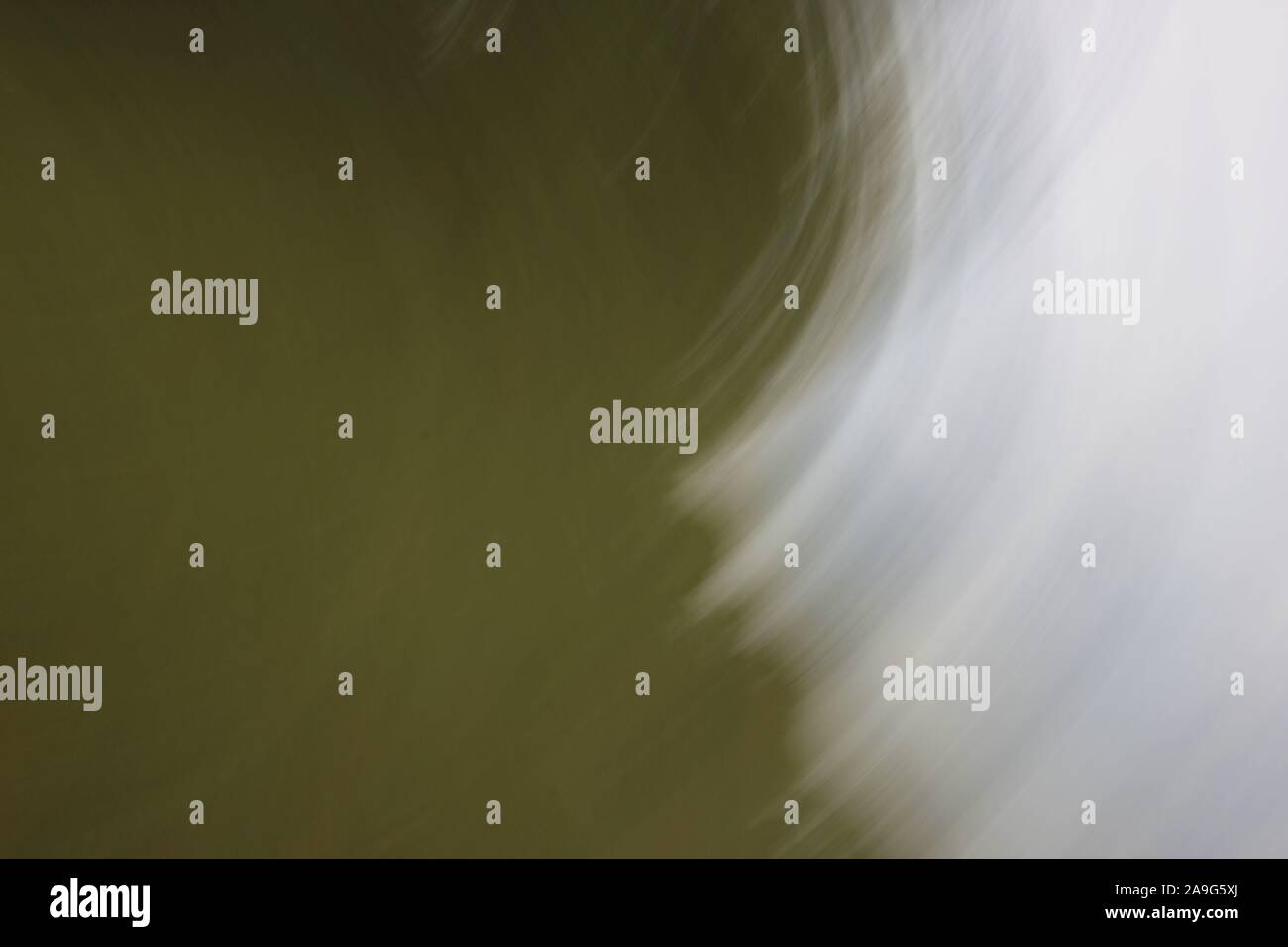 Immagine astratta che mostra striature sfocate di luce bianca o di colore contro sfumature di verde in background Foto Stock