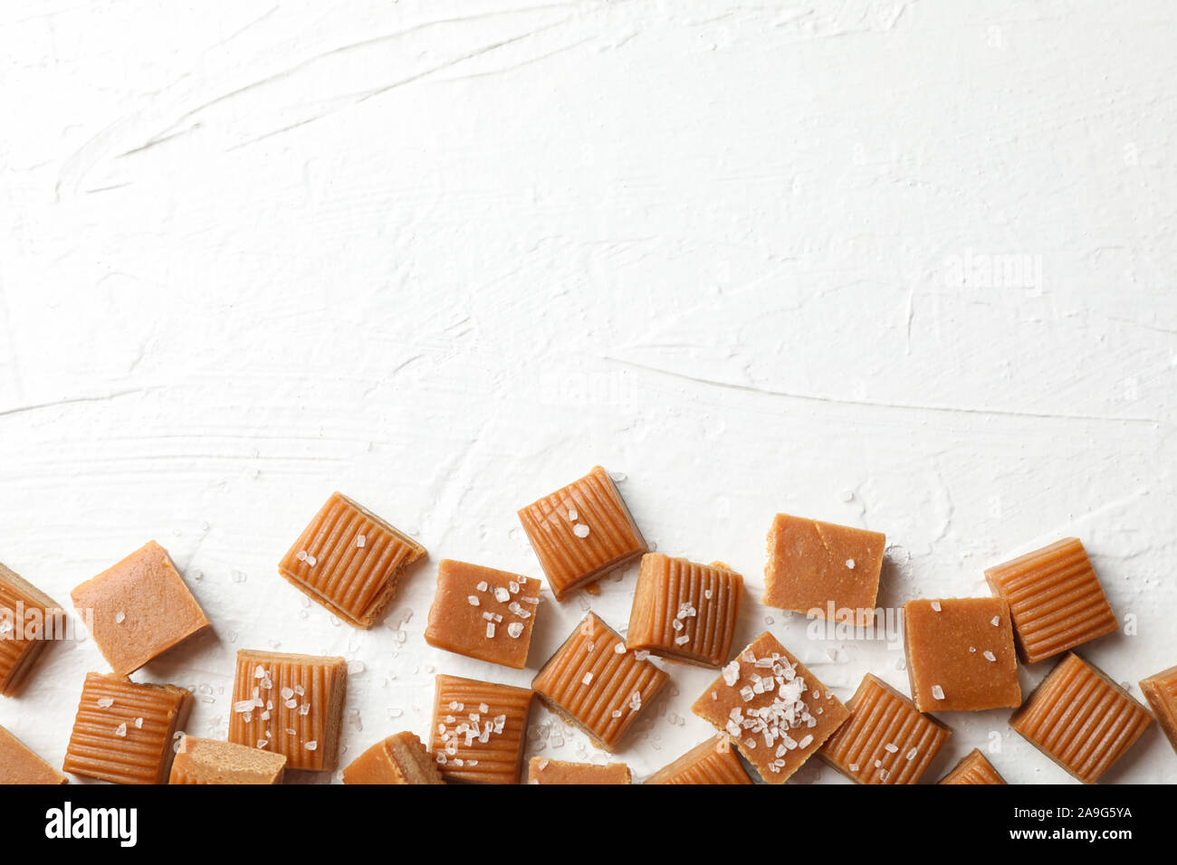 Salate caramello caramelle sul cemento bianco sfondo, spazio per il testo Foto Stock